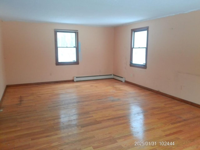 spare room with a baseboard heating unit and light wood-type flooring