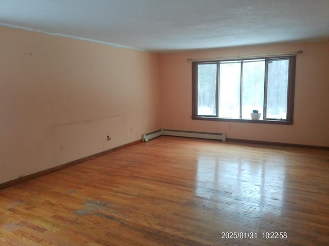 empty room featuring a baseboard heating unit and hardwood / wood-style flooring