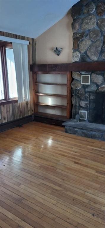 unfurnished living room with hardwood / wood-style flooring, lofted ceiling, and a fireplace