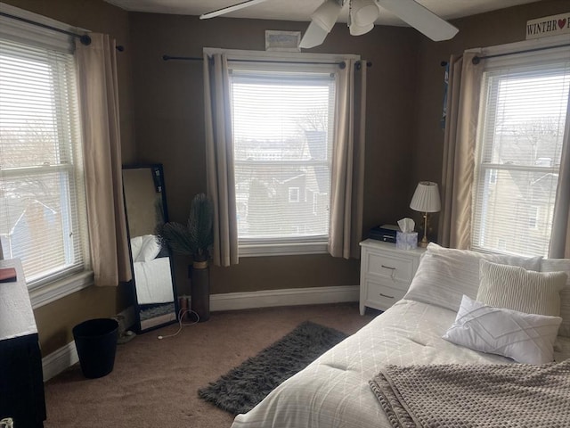 carpeted bedroom featuring multiple windows, baseboards, and a ceiling fan