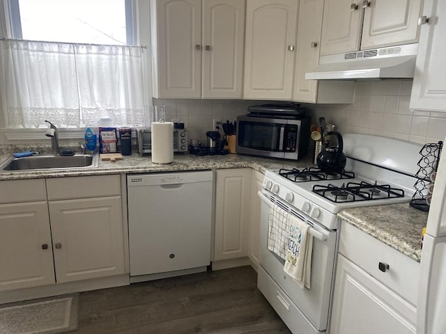 kitchen featuring white appliances, wood finished floors, under cabinet range hood, white cabinetry, and a sink