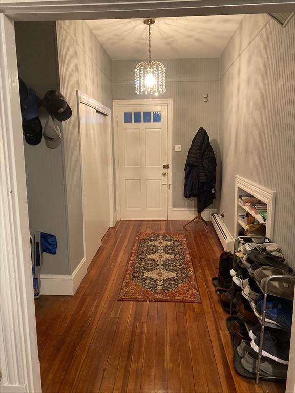 doorway featuring a chandelier, wood-type flooring, baseboards, and baseboard heating