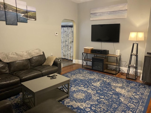 living area with arched walkways, wood finished floors, and baseboards