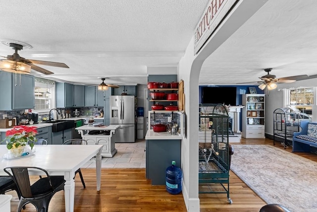 kitchen with light countertops, stainless steel refrigerator with ice dispenser, light wood finished floors, and a sink