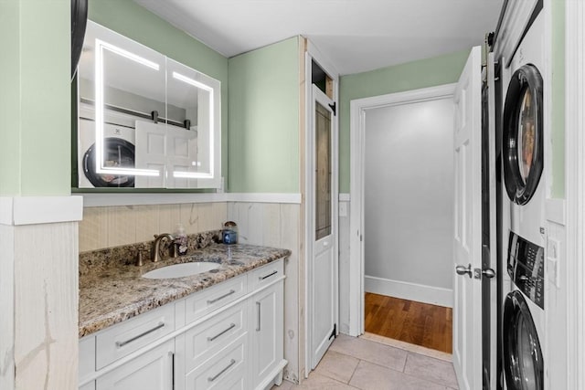 bathroom featuring tile patterned floors, wainscoting, vanity, and stacked washing maching and dryer