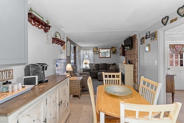 dining space with a fireplace and ornamental molding