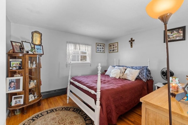 bedroom with wood finished floors and a baseboard radiator