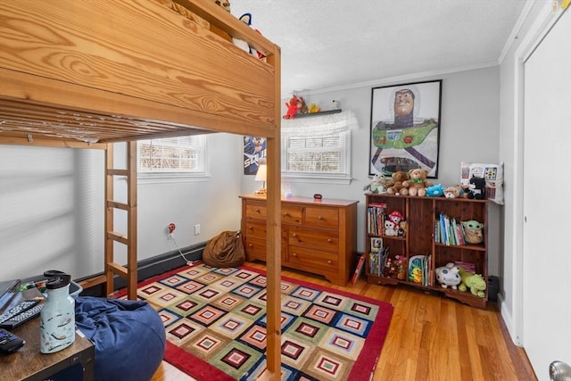 bedroom featuring crown molding, wood finished floors, and baseboards