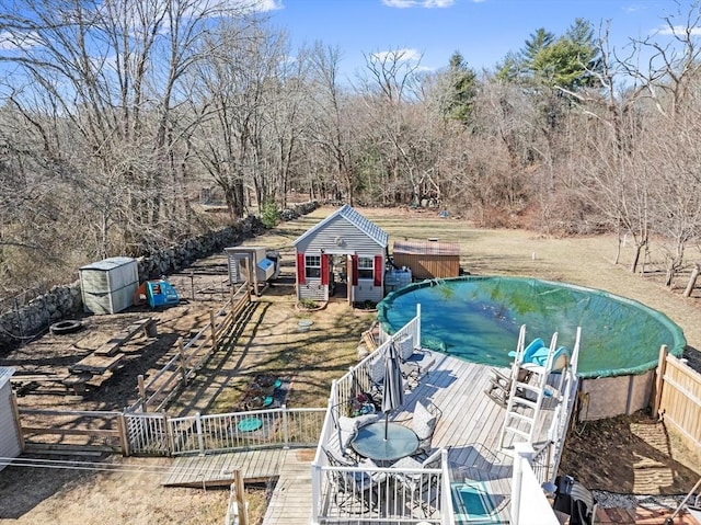 view of swimming pool featuring an outbuilding, a wooden deck, and fence