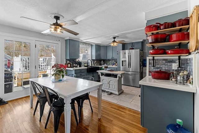 dining space with a ceiling fan, light wood-style floors, and a textured ceiling