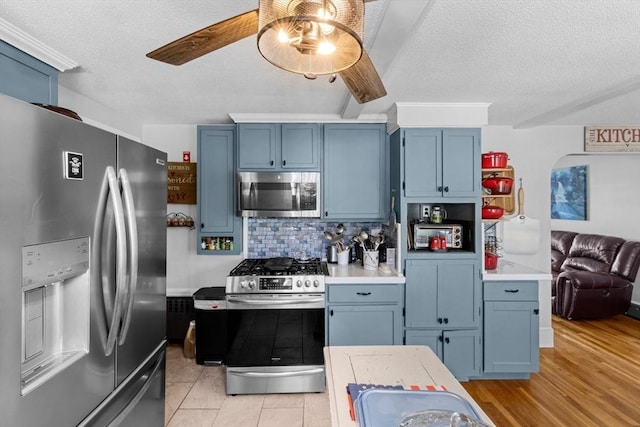 kitchen with backsplash, stainless steel appliances, blue cabinets, and light countertops