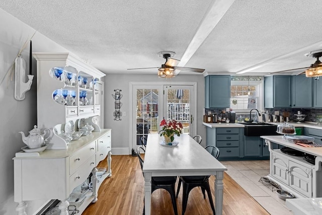 kitchen with blue cabinetry, ceiling fan, decorative backsplash, light countertops, and a sink