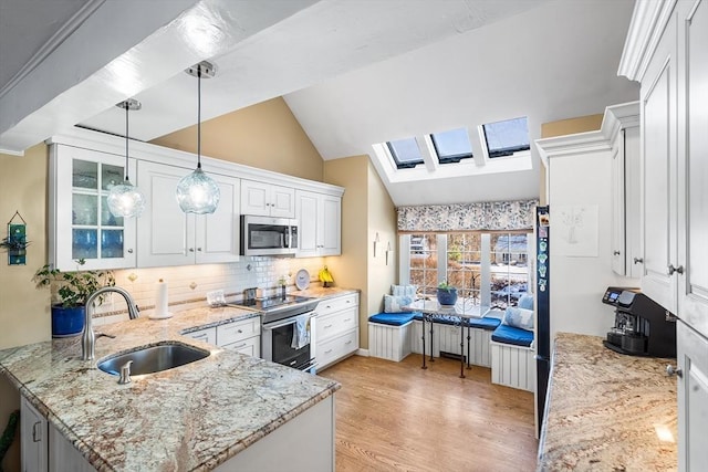 kitchen featuring sink, light stone counters, decorative light fixtures, appliances with stainless steel finishes, and white cabinets