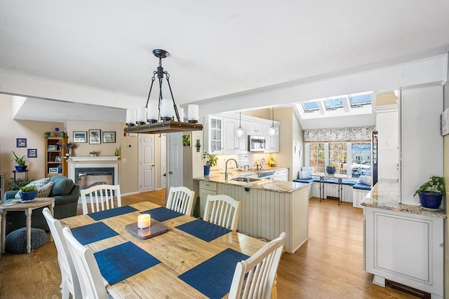 dining area featuring sink, vaulted ceiling, and light hardwood / wood-style floors