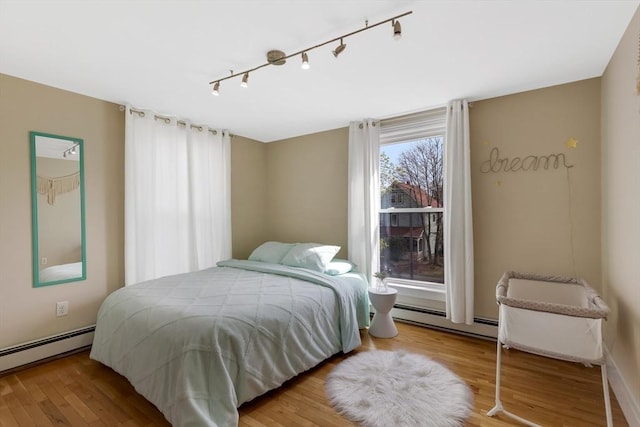 34 Warren St Unit 3, Stoneham, MA 02180 - bedroom featuring a baseboard heating unit, rail lighting, and wood finished floors
