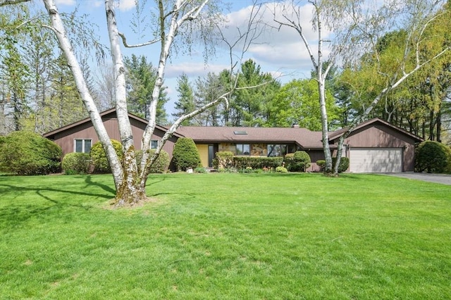 ranch-style home featuring an attached garage, a front yard, and aphalt driveway