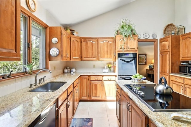 kitchen featuring a sink, light stone counters, light tile patterned floors, and black appliances