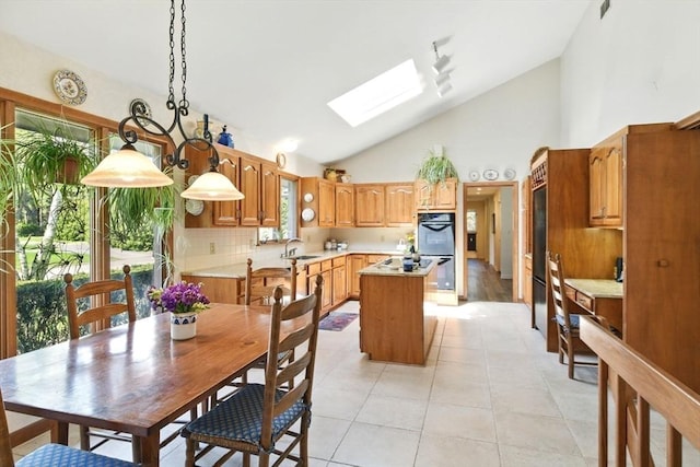 dining room with a skylight, high vaulted ceiling, and light tile patterned flooring