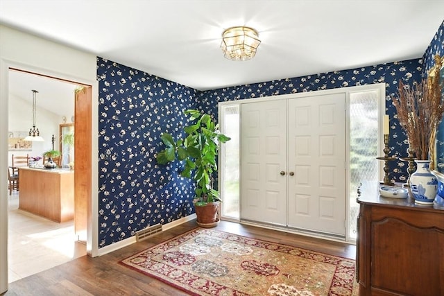 entryway with plenty of natural light, wallpapered walls, and wood finished floors