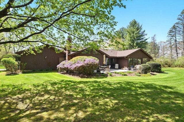 rear view of property with a yard, a patio, and a chimney