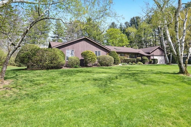 view of property exterior featuring an attached garage and a lawn