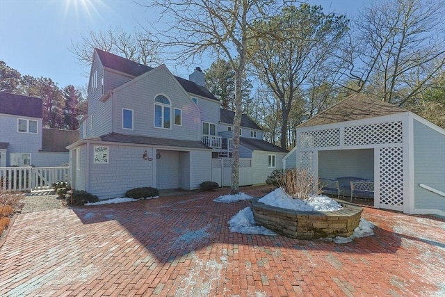 rear view of house with a chimney, fence, and a gazebo