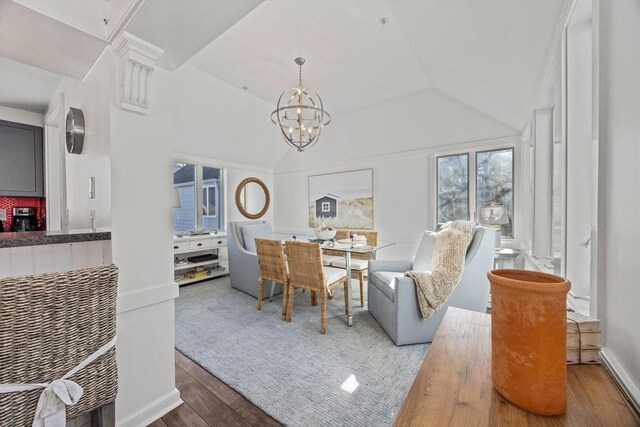 living room featuring vaulted ceiling, an inviting chandelier, and wood finished floors