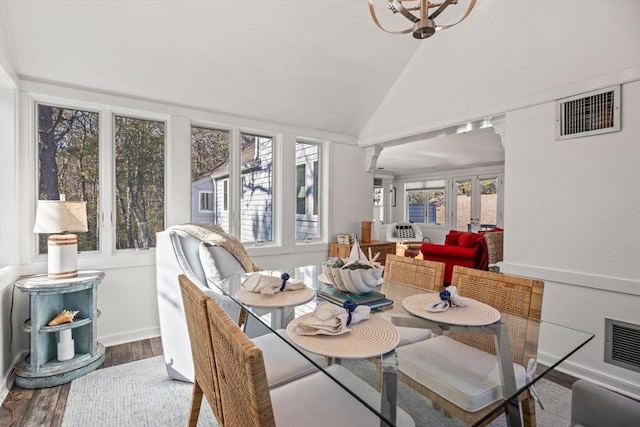 dining space with decorative columns, visible vents, vaulted ceiling, and wood finished floors