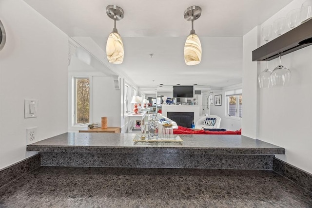 kitchen featuring dark countertops, pendant lighting, a fireplace, and open floor plan