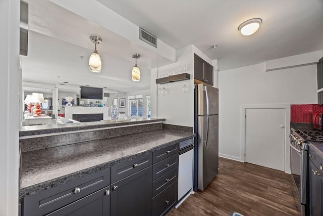 kitchen featuring pendant lighting, dark wood finished floors, stainless steel appliances, dark countertops, and visible vents