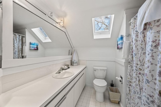 bathroom with a shower with shower curtain, toilet, lofted ceiling with skylight, tile patterned flooring, and vanity