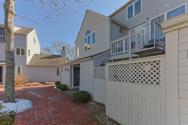 rear view of house with a balcony and fence