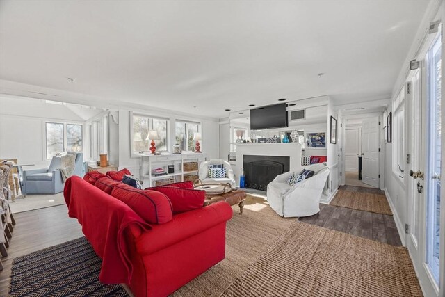 living room featuring a fireplace, visible vents, and wood finished floors