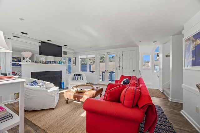 living room with french doors, a fireplace, wood finished floors, and baseboards