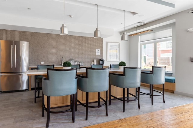 kitchen with stainless steel fridge, a breakfast bar, and hanging light fixtures