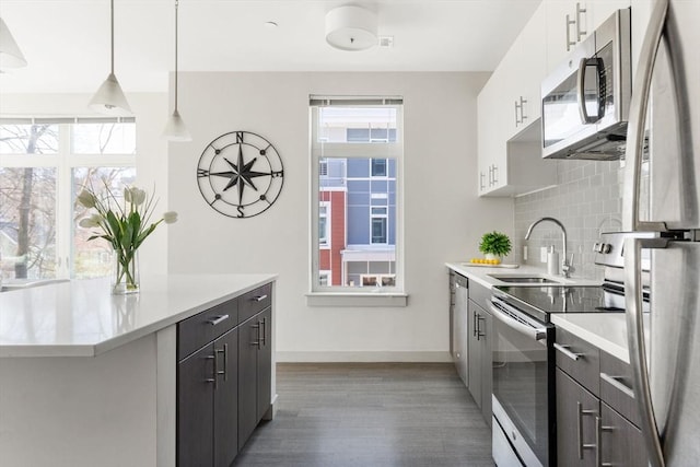 kitchen with decorative backsplash, appliances with stainless steel finishes, sink, pendant lighting, and white cabinets