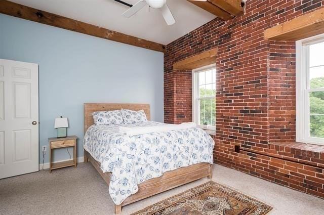 carpeted bedroom with ceiling fan, brick wall, and beam ceiling