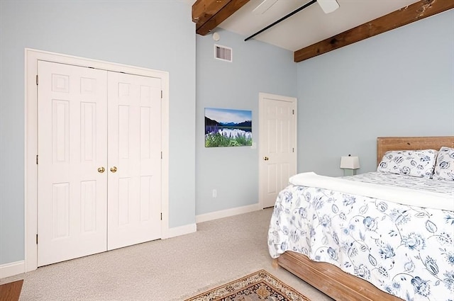 bedroom with ceiling fan, light colored carpet, a closet, and beamed ceiling