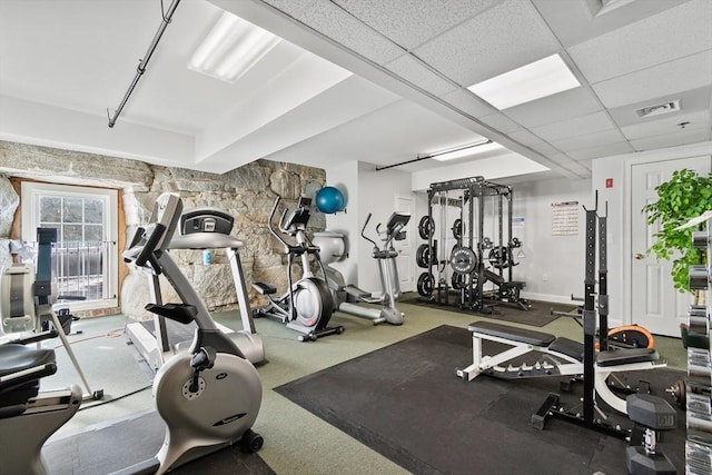 exercise room featuring carpet floors and a drop ceiling