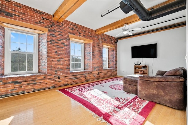 living room featuring ceiling fan, brick wall, and beamed ceiling