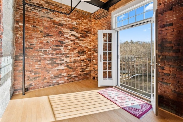 doorway to outside featuring brick wall and light wood-type flooring