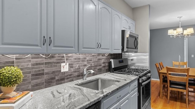 9 Longwood Dr Unit 11, Andover, MA 01810 - kitchen with appliances with stainless steel finishes, a chandelier, decorative backsplash, light wood-style flooring, and light stone countertops