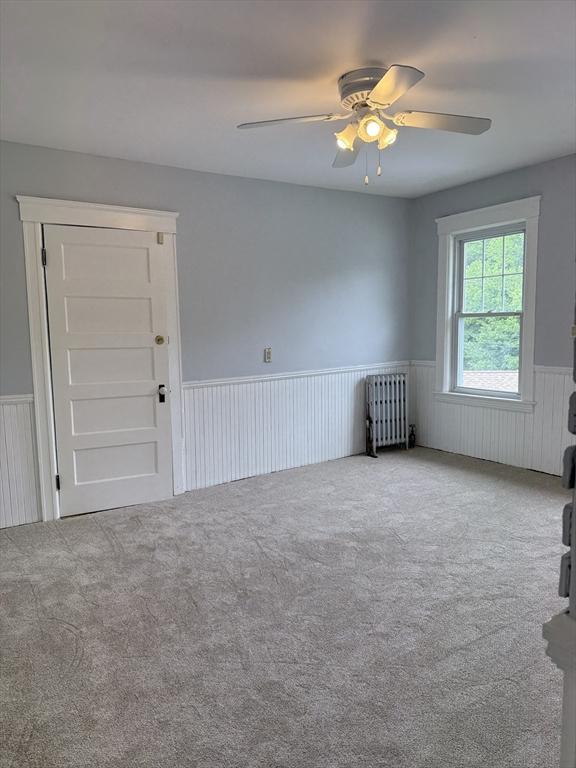 612 Grove St Lot 1, Worcester, MA 01605 - carpeted empty room with radiator heating unit, a wainscoted wall, and a ceiling fan