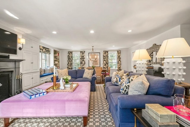 living room featuring built in shelves, ornamental molding, recessed lighting, a fireplace, and a chandelier