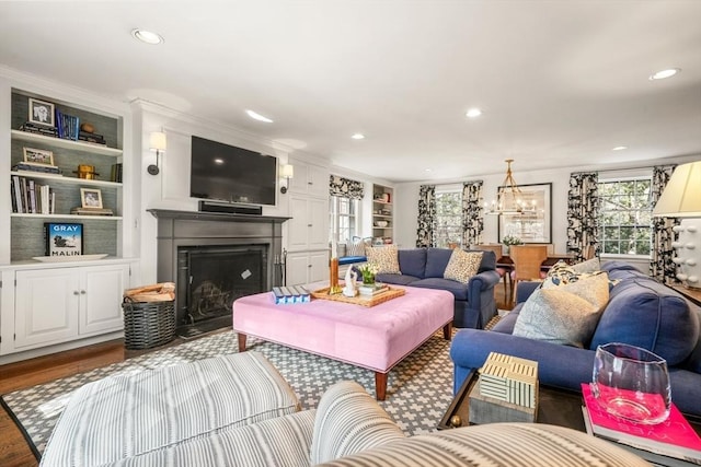 living room with recessed lighting, built in shelves, wood finished floors, and a fireplace