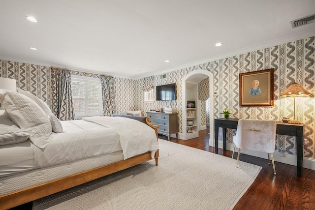 bedroom featuring wood finished floors, visible vents, wallpapered walls, arched walkways, and crown molding