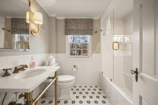 bathroom with a wealth of natural light, toilet, tile walls, and crown molding