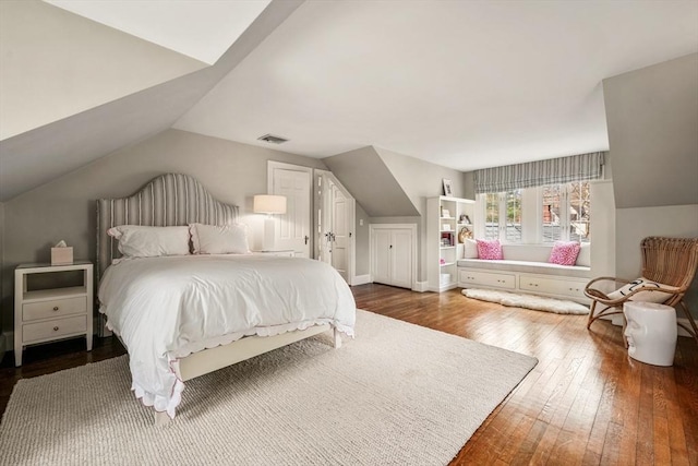 bedroom with visible vents, hardwood / wood-style floors, and vaulted ceiling