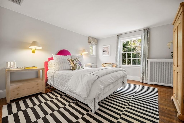 bedroom with visible vents, baseboards, wood finished floors, and radiator heating unit