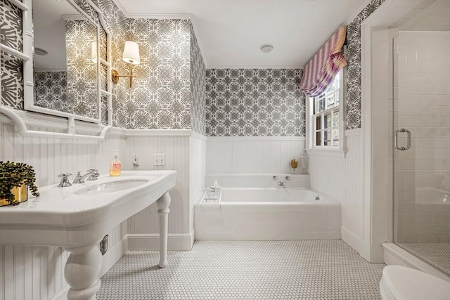 bathroom featuring toilet, a stall shower, wainscoting, wallpapered walls, and a bath